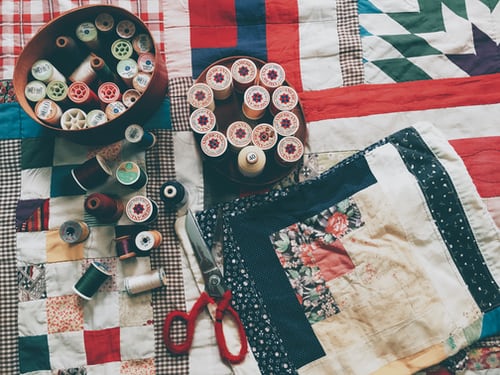 Cotton and sewing scissors on a patchwork quilt